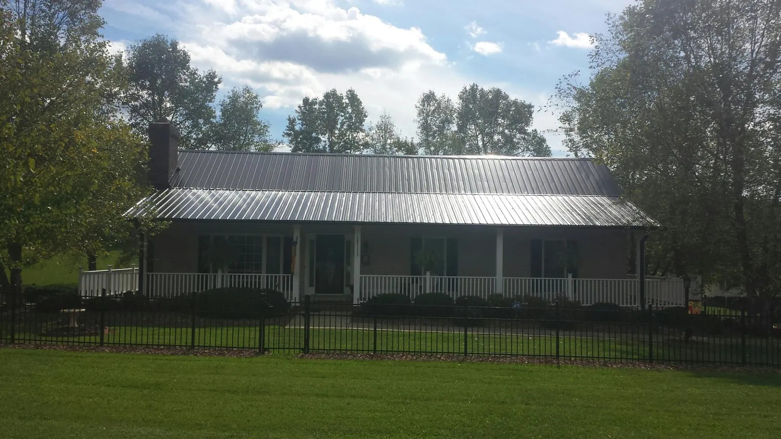 Gray metal roof on a brick ranch with a full width front porch — Gutter Guard Installation work by our crew in Portsmouth