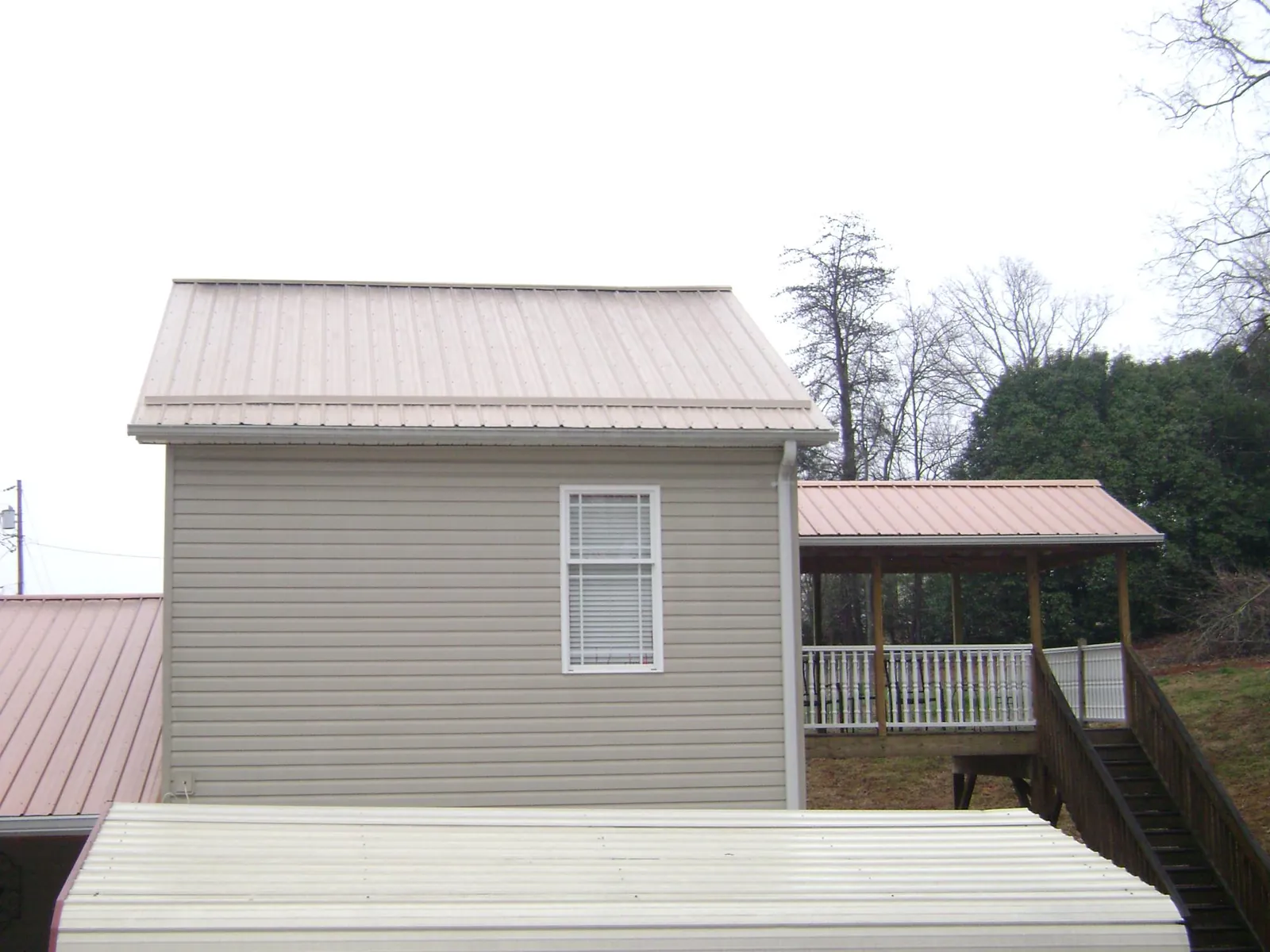 Tan metal roofs on a two story addition and attached porch, from a Roof Replacement job in Portsmouth